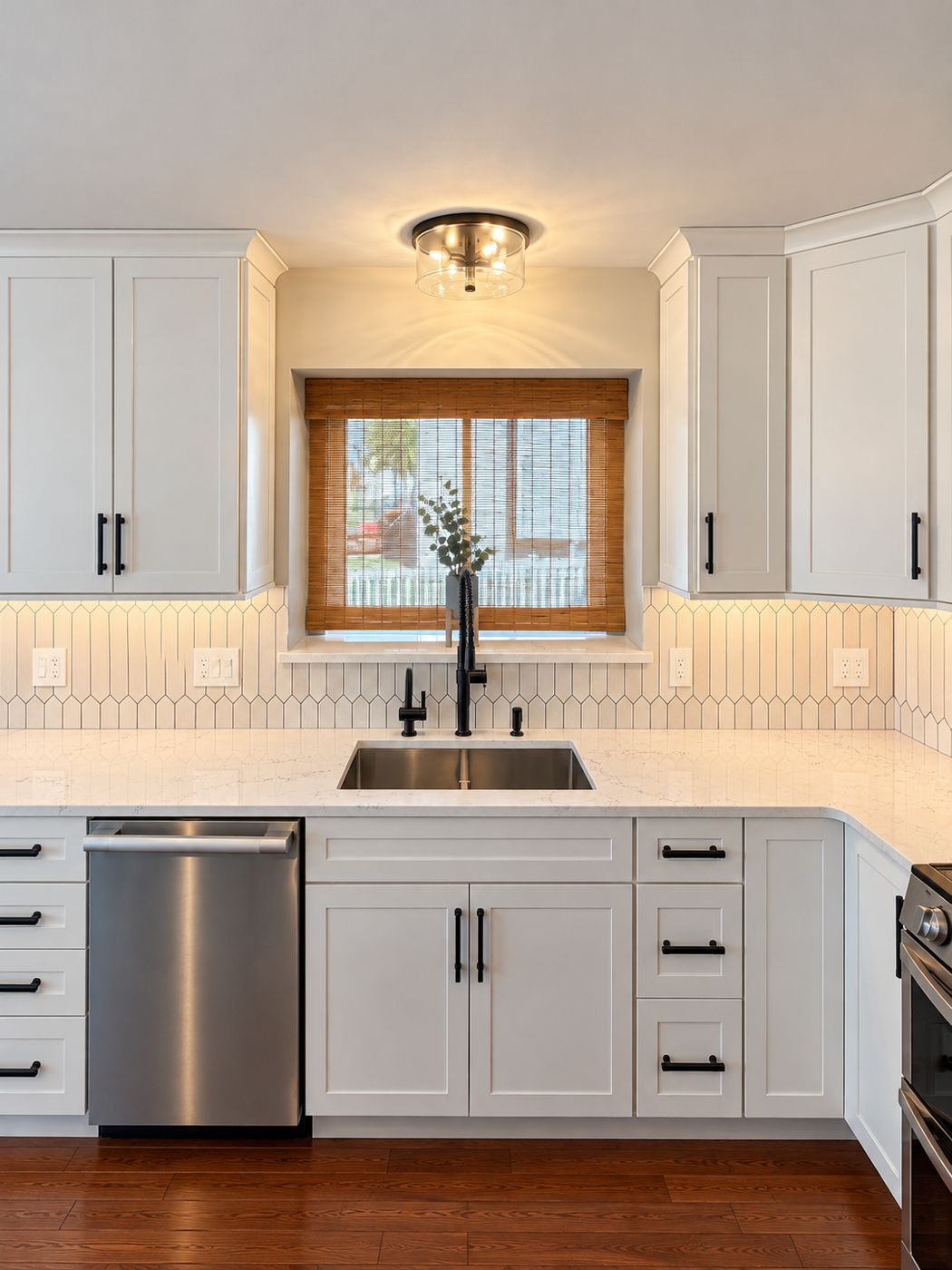 Kitchen sink with matte black faucet below a window with a woven shade
