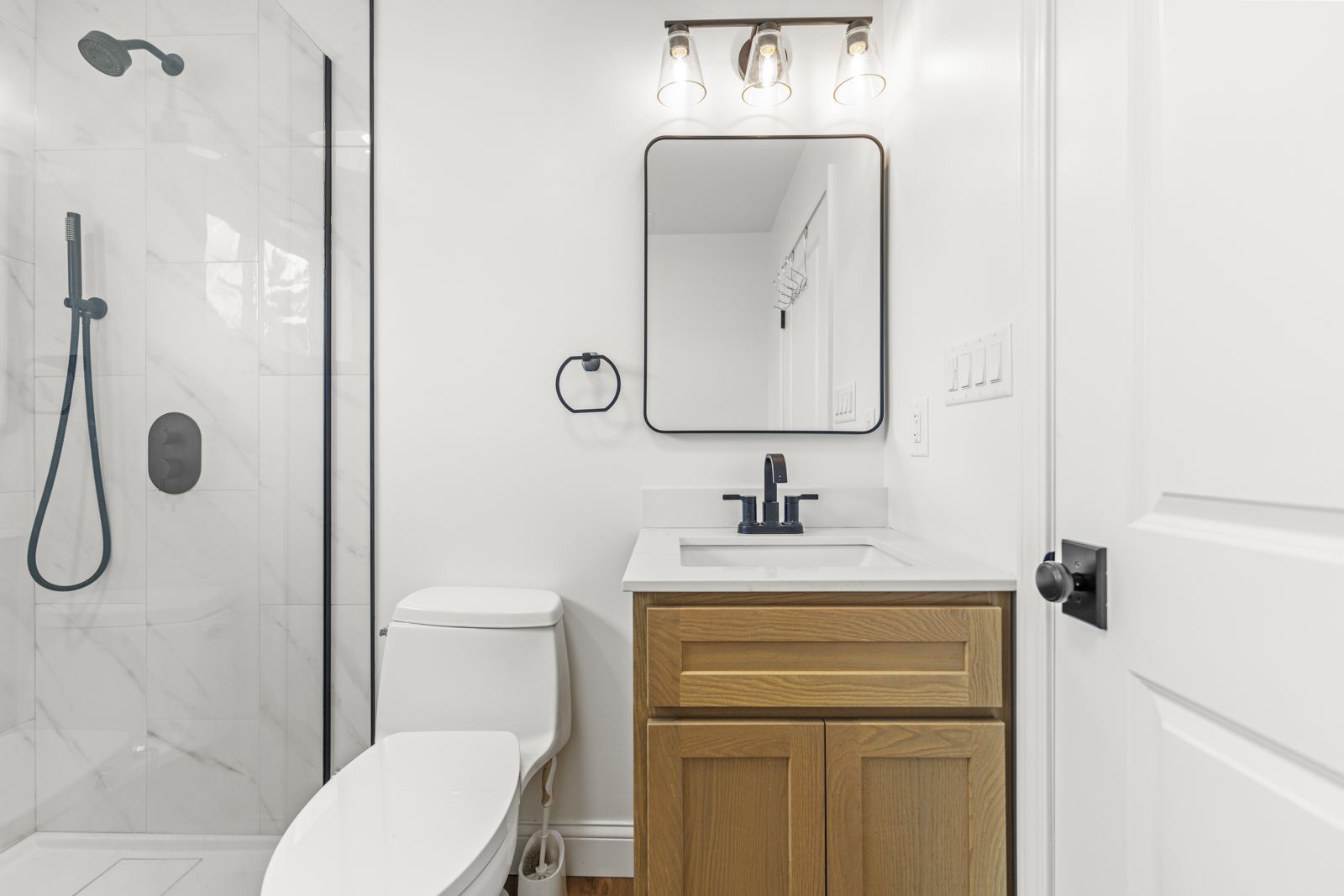 Oak vanity with quartz top, black faucet, and framed mirror