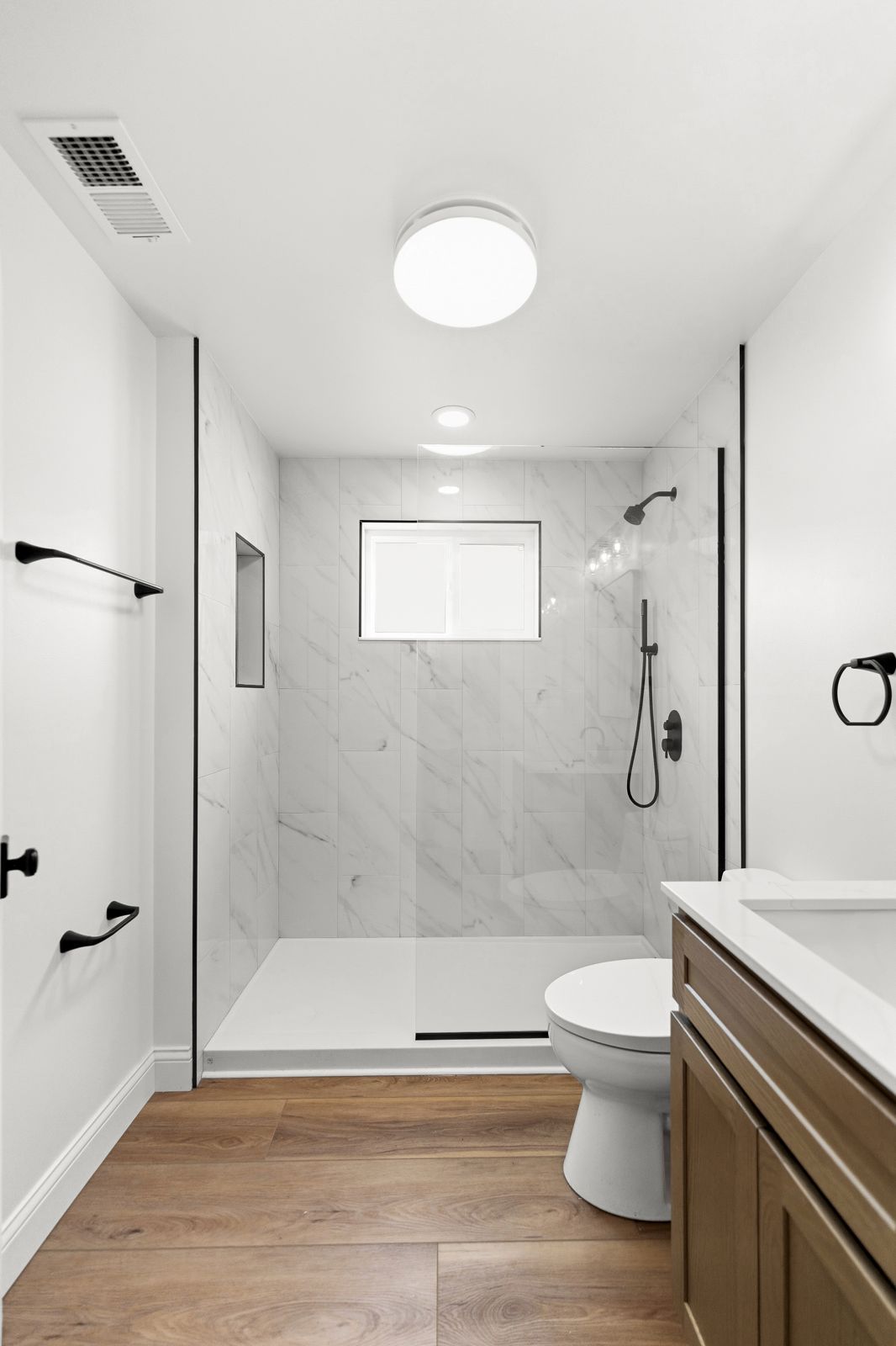 Bathroom with tiled shower and wood-look floor