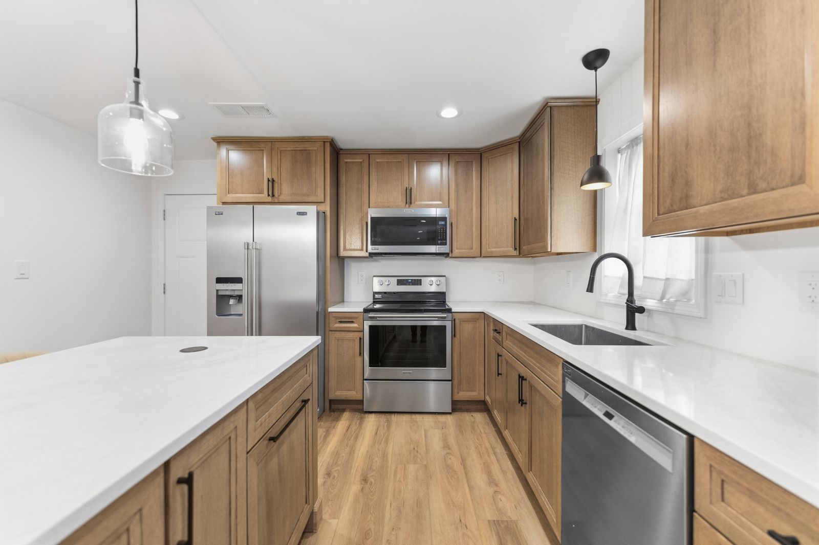 Corner of the oak kitchen with stainless refrigerator and range